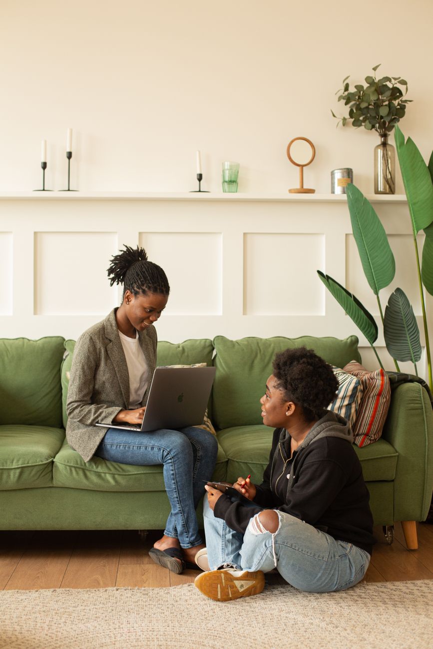 Two women chatting on a sofa with a laptop