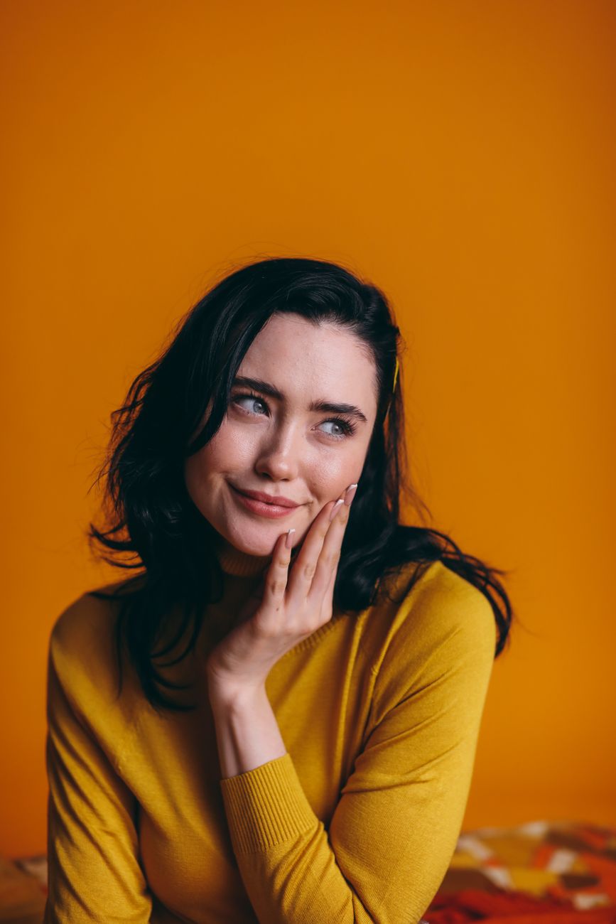 Woman in a yellow sweater against a yellow backdrop
