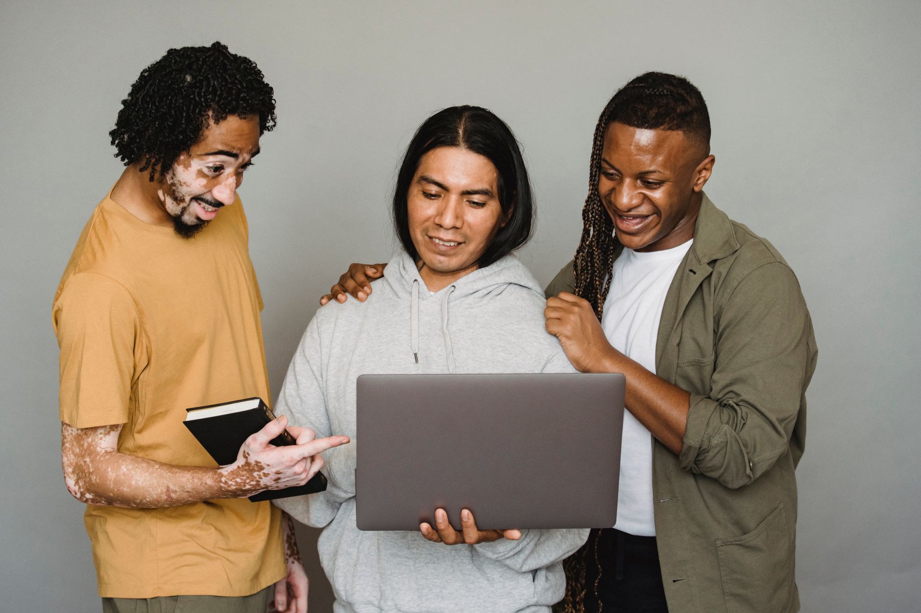 Three colleagues smiling together around a laptop